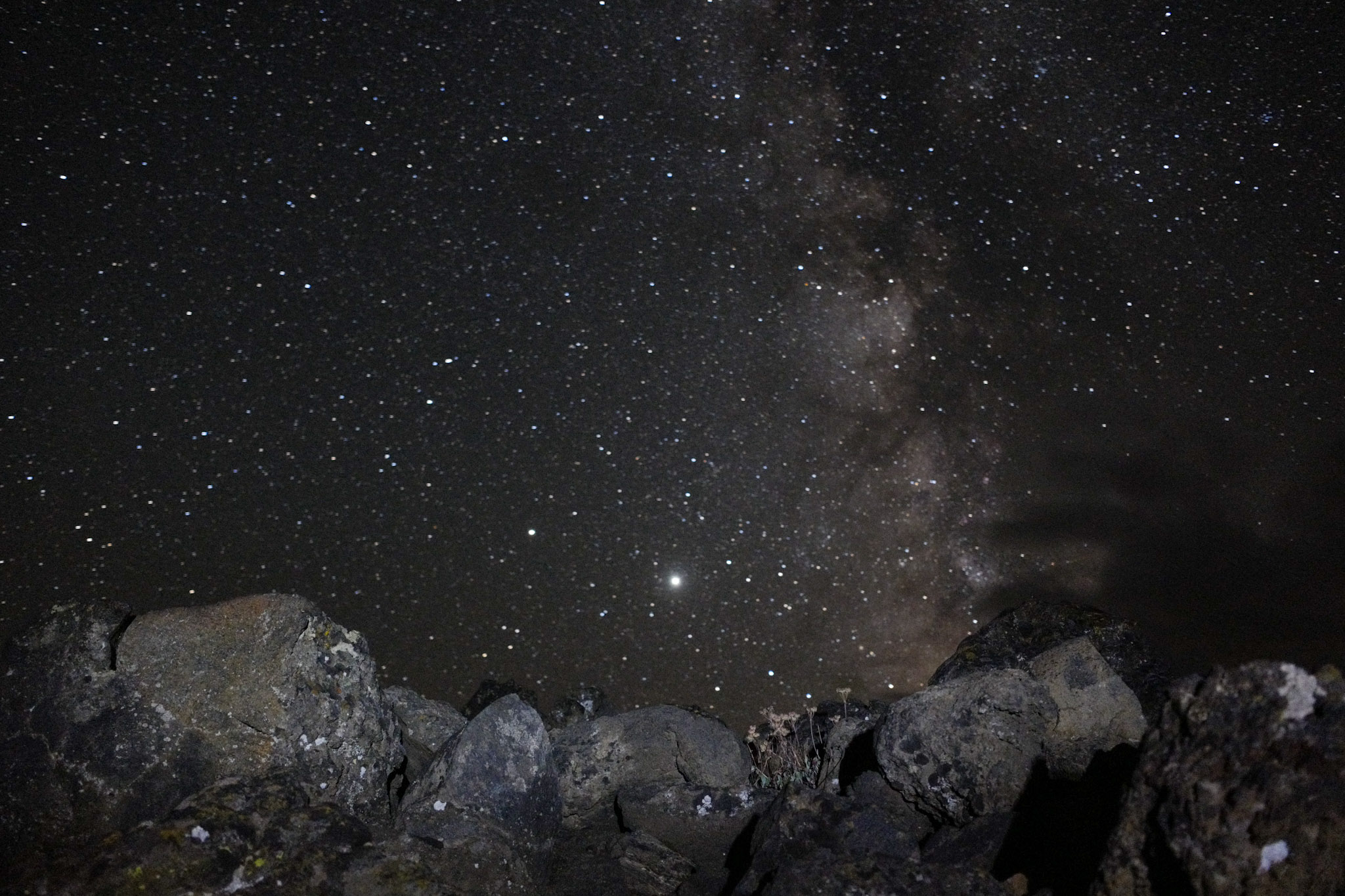 Night sky full of stars over a dark mountain ridge